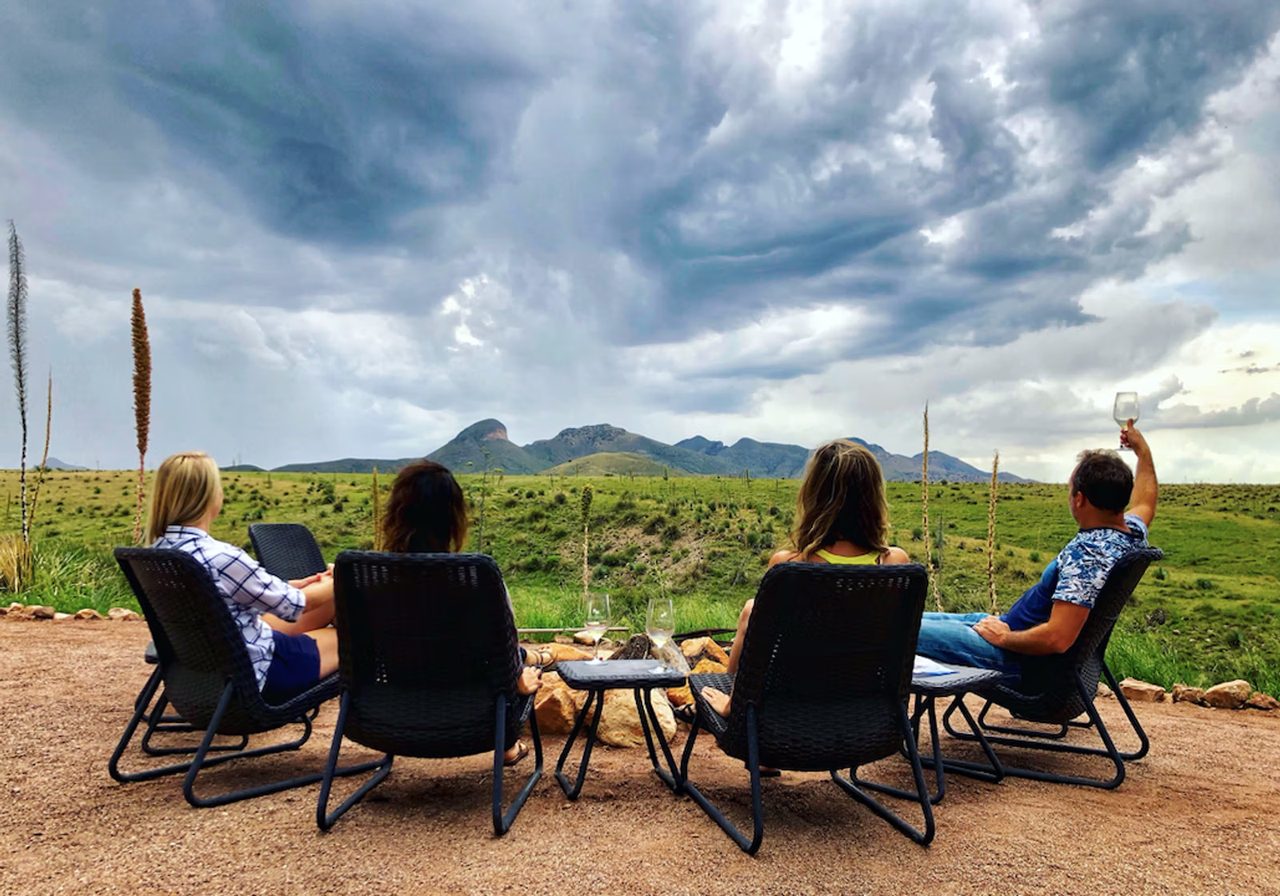 Guests with a glass of wine looking out over the Sonoita grasslands at Rune Wines